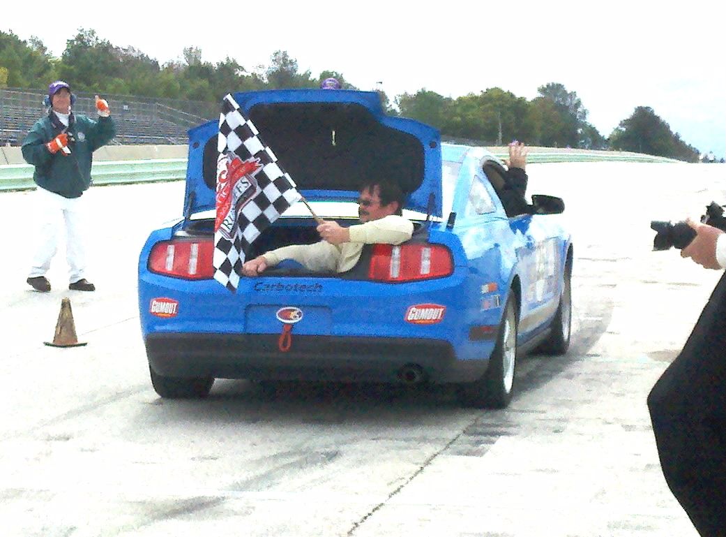 Chris Childs celebrating in the trunk of a Mustang with the checkered flag